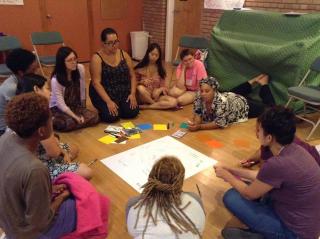 a group of women of color sit around a piece of chart paper
