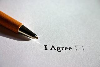 A pen pointing to the words "I agree" with an empty check box.