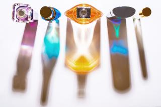 Five glass perfume bottles, photographed from above, with the colored reflections of their different sizes and shapes.