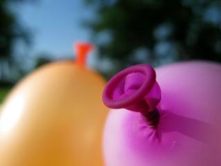 A close up of a bright orange and bright pink ballon, inflated, with their tied-off ends visible.