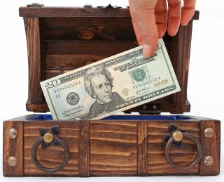 hand taking a $20 bill out of a wooden box
