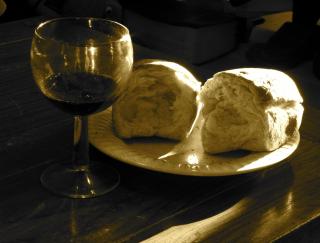A sepia-tone photo of a broken loaf of bread and a glass of red wine