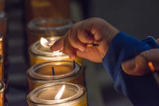 Child's_hand_lighting_votive_candle
