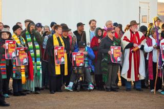 At least two dozen clergy members, in vestments, representing a number of faith traditions, at Standing Rock