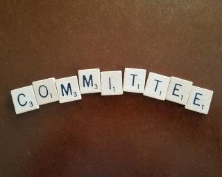 The word committee spelled out in Scrabble tiles