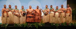 Performers from Fiji wearing traditional dress stand on a stage at COP23