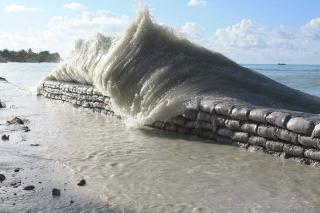 A large wave overcoming a barrier on an island beach