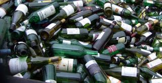 A pile of empty green and brown wine and liquor bottles.