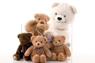 An assortment of teddy bears of different colors and sizes in a doll bed