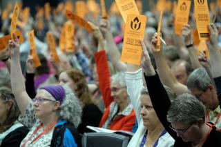 Delegates hold bright orange voting cards aloft to vote in General Session