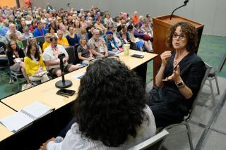 Two women engage in a panel discussion in front of several hundred audience members