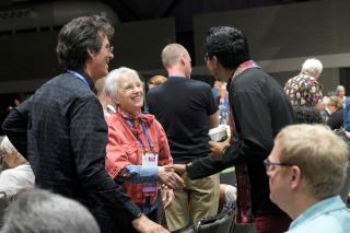A white-haired GA attendee shakes hands with a worship leader, who is a person of color.