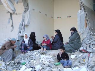 A Muslim family in Jabalia sits on the rubble inside the bombed out walls of their former home