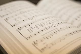 An open hymnal, most of the text and music blurred.
