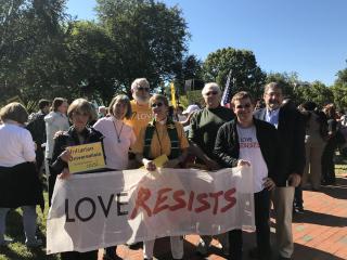 a group of people stand outside holding a Love Resists banner