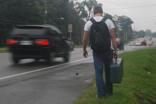 Man on roadside carrying suitcase.