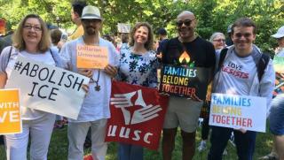UUA and UUSC staff holding signs that say Families Belong Together and #AbolishICE
