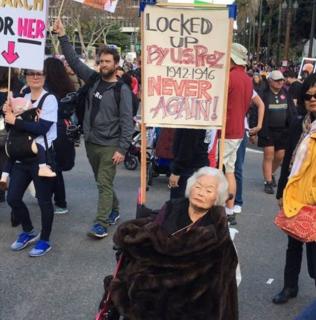 Woman using a wheelchair holds a sign reminding national Women's Marchers about the internment of Japanese Americans in the 1940s.