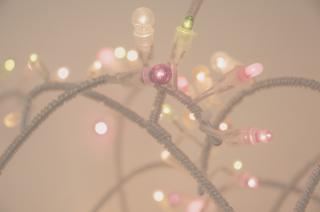 A hazy, pink-tinged photo of christmas lights in purple, green, and white