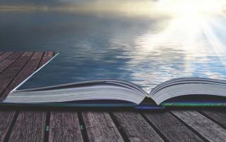 Image of an open book opening into the ocean and shining sun.