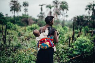 A baby is carried on her mother's back in a typical West African pagne: a brightly colored piece of cloth.