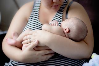 A woman cradles a sleeping infant, gazing down at their face