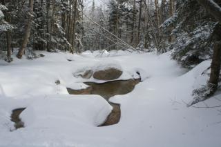 Mountain stream in winter, snow upon ice.
