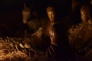 Figures from a nativity creche, including an adult figure gazing at the infant Jesus