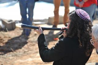 A rabbi wearing a yarmulke blows the sheep's horn known as a shofar.