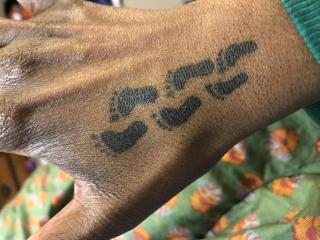 Three sets of footprints tattooed onto Rayla Mattson's hand.