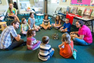 Children and teachers sitting in a circle around a chalice.
