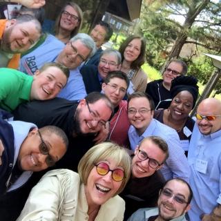 More than a dozen UU religious professionals who are transgender smile during a retreat.