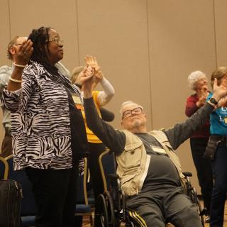 Two participants in the 50th Anniversary of the Selma Voting Rights campaign hold their raised hands in prayer.