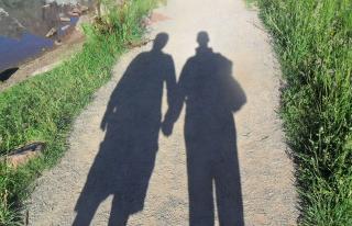 The shadow of two people holding hands is cast along an outdoor path.