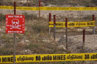Tape warning of landmines surrounds a dangerous zone of land in Sri Lanka.