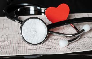 Stethoscope and paper heart laying on an ekg readout