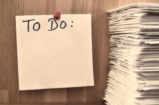  A blank to do list on the wall next to a large stack of papers