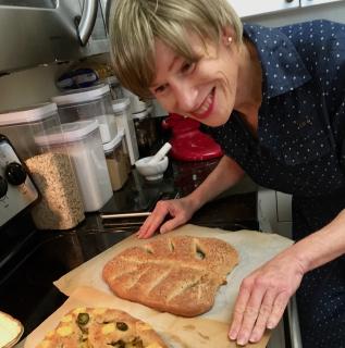 A woman in a kitchen leaning over  freshly baked bread