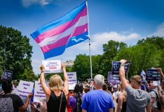 A large trans flag is held aloft at the 2019 Rally to Protect Trans Health, at the White House, Washington, DC.