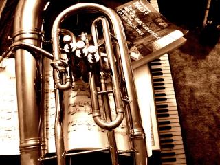 a tuba, piano, and sheet music in a sepia tones