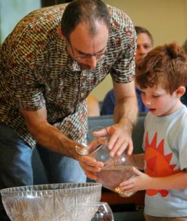 Man and child pour water into the common bowl.