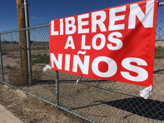 A sign reads "Free the Children" on the gates of the Tornillo detention center, where unaccompanied minors are held in a remote desert tent camp.
