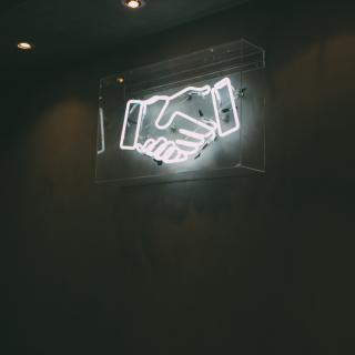Glowing sign with hands shaking