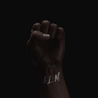 A black person's fist against a dark background, with "BLM" written on their wrist.
