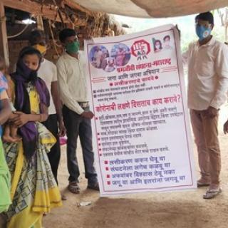 Group of people wearing protective masks during COVID-19 surge in India. Two in the center hold a medical informational sign written in Hindi.