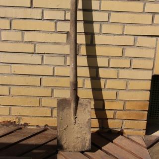 Spade with mortar in front of a brick wall