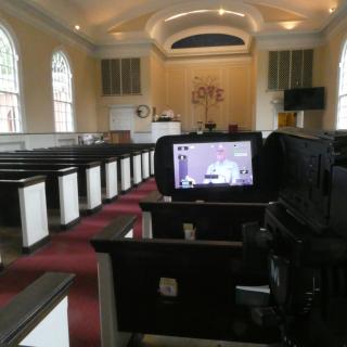 Video camera in foreground with pulpit in view screen and in the distance.