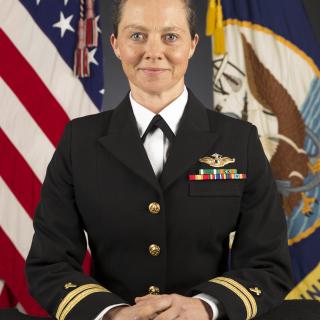 In her formal military portrait, Susan Maginn poses solemnly in her dress uniform in front of the US flag.