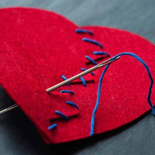 a red felt heart, stitched back together up the center with blue thread and a needle