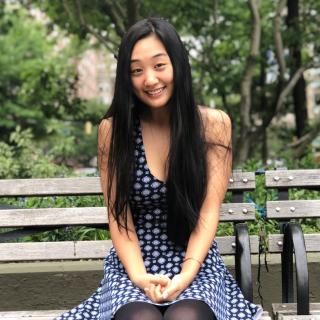 Photo of Alisha Zou sitting on a park bench and smiling